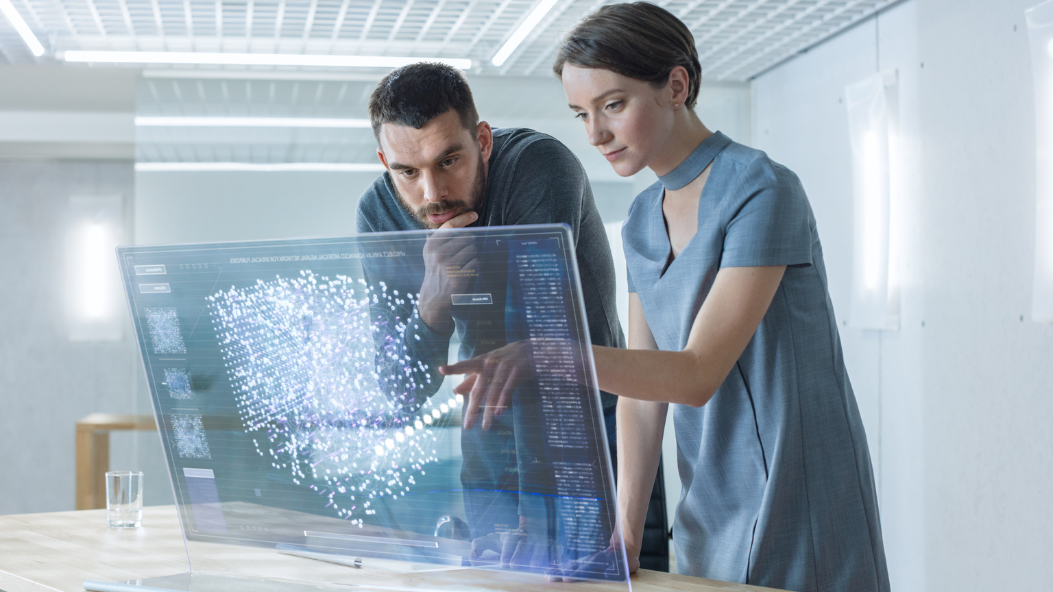 In the Near Future Male and Female Computer Engineers Talk While Working on the Transparent Display Computer. Screen Shows Interactive Neural Network, Artificial Intelligence Project, Futuristic User Interface.